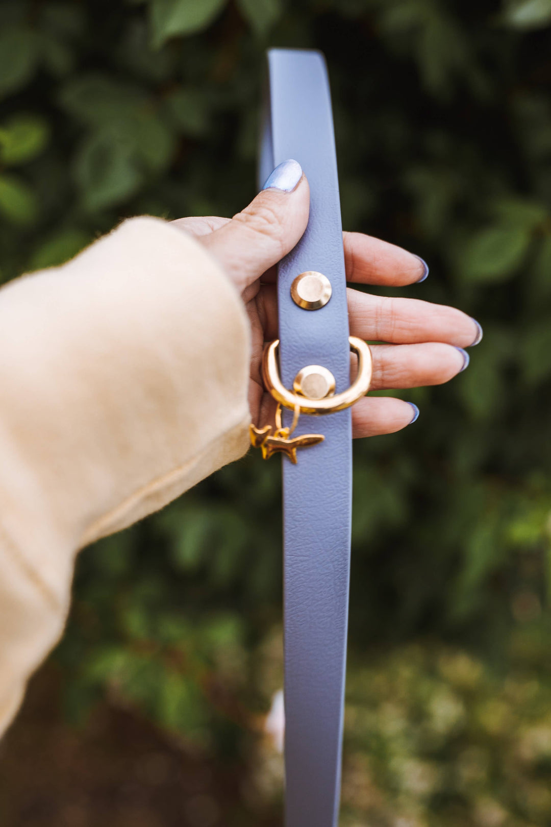 Person holding up a lavender waterproof Biothane signature dog leash with solid brass hardware.