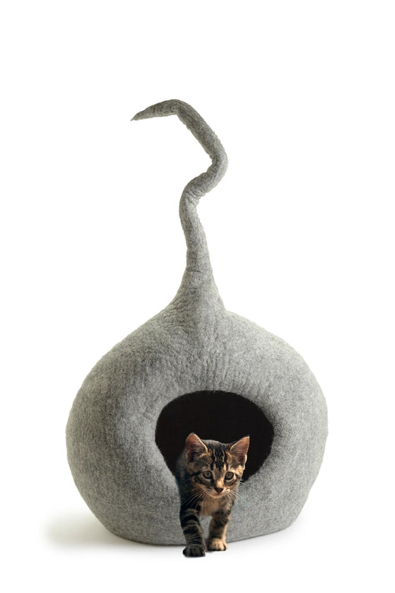 Cat peeking out from a gray felted cat house on a white background