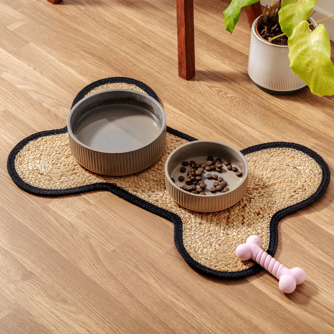 Loxley Pet Placemat with two bowls and a dog bone beside it – eco-friendly jute bone-shaped feeding mat